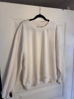 Vit oversized sweatshirt Lager 157 - Vit oversized sweatshirt från Lager 157 med rund halsringning och långa ärmar. Tröjan har en enkel och clean design med ribbade muddar vid ärmslut och nederkant. Perfekt för en chill och avslappnad stil.