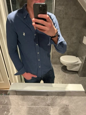 Blå skjorta från Ralph Lauren - Säljer en riktigt snygg skjorta från Ralph Lauren i mesh material. Skjortan är i bra skick och har inga defekter. Jag på bilden är 188cm. Hör av er vid frågor eller prisförslag:)