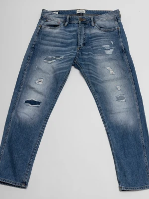 Blå slitna jeans från Jack & Jones - Säljer ett par blå jeans från Jack & Jones med snygga slitningar och hål på framsidan. Jeansen har klassisk femficksmodell, normal midja och raka ben. Tillverkade i denim med en tvättad look som ger en avslappnad vibe.