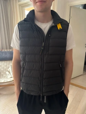 Svart dunväst från Parajumpers - Snygg svart dunväst från Parajumpers med gul detalj vid kragen och två dragkedjeförsedda fickor. Nypris 4000 köpt på hanzens. På insidan finns en liten defekt som ej är synlig då den är på insidan! Har heller inte testat tvätta bort den så det går nog. 