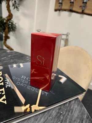 Giorgio Armani Sì Passione parfym - Giorgio Armani Sì Passione parfym i en elegant röd förpackning med gulddetaljer. Flaskan har en stilren och lyxig design som verkligen sticker ut. Perfekt för dig som gillar exklusiva dofter och vill ha något som känns både modernt och klassiskt.
