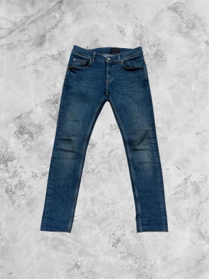 Slim fit Tiger of Sweden jeans - Säljer ett par klassiska blå slim fit jeans från Tiger of Sweden med fem fickor och snygga slitningar på framsidan. Dom är W30 L32 och måtten står i bild 3 och 4.