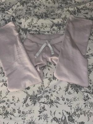 Ljuslila mjukisbyxor med dragsko - Mysiga ljuslila mjukisbyxor med vit dragsko i midjan och ribbade muddar vid benslut. Bakficka med broderad detalj. Perfekta för chill eller slappa dagar. Tillverkade i mjukt bomullsmaterial.