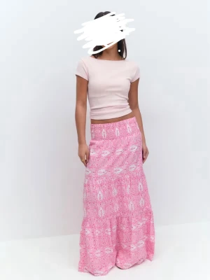 Rosa långkjol med vit blommigt mönster - Säljer en rosa långkjol med vitt blommigt mönster. Kjolen har en bred resår i midjan och är luftig med ett flowigt fall. Perfekt för dig som gillar färg och mönster. Passar till både t-shirt och topp.