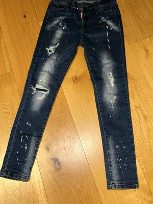 Mörkblå distressed jeans Dsquared2  - Snygga mörkblå jeans från Dsquared2 med slitningar, färgstänk och skinny fit. Jeansen har klassisk femficksdesign och coola detaljer som ger en trendig look. Perfekta för dig som gillar streetstyle och vill sticka ut. Knappt använd också. (Slimfit jeans)