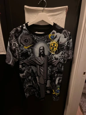 Nike Brasil tshirt - Cool t-shirt från Nike med Brasil-motiv och Dri-Fit material. Svart och grå med detaljer i gult och blått, och ett stort tryck av Kristusstatyn på framsidan. Perfekt för sport eller att hänga med kompisar. Aldrig nånsin använd!😁
