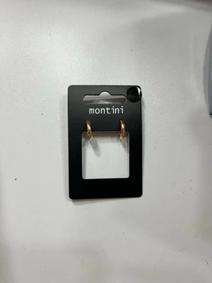 Guldfärgade hoops från Montini - Snygga små örhängen i guldfärgad metall från Montini. Klassisk hoop-modell som är enkla att matcha med olika stilar. Perfekta för dig som gillar minimalistiska accessoarer och vill ha något stilrent i smyckeslådan. Helt oanvända!