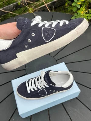 Mörkblå Philippe Model sneakers - Innan ni läser dethär, skicka ett prisförslag om priset är för dyrt! Pris kan diskuteras!!!!Snygga mörkblå sneakers från Philippe Model med vita detaljer och vita skosnören. Skorna har en klassisk låg siluett, emblem på sidan och är tillverkade i mocka och läder. Perfekta för en stilren och trendig look. Väldigt snygga skor, och väldigt sköna om jag får säga det själv. Det står i skorna att det är storlek 45 men själv skulle jag säga att dem känns som 43,1/4