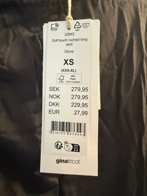 Grå långkjol från Gina Tricot XS - Snygg långkjol i mjukt material från Gina Tricot i färgen stone. Kjolen har en ruched detalj på sidan som ger en cool och trendig look. Perfekt för dig som gillar stilrena plagg med en twist. Aldrig använd endast provad.