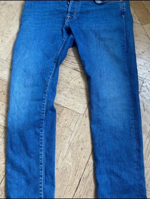 Blå jeans från Jacob Cohen - Säljer ett par klassiska blå jeans från Jacob Cohen. De har en rak passform, fem fickor och snygga kontrastsömmar. Jeansen är tillverkade i mjukt denimtyg och har en patch med logga bak i midjan. Perfekta till vardagslooken!