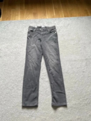 Grå raka jeans 158 cm - Säljer ett par grå jeans med rak passform och klassisk femficksdesign. Jeansen har knapp- och dragkedjegylf samt bälteshällor. Perfekta för en avslappnad och stilren look.