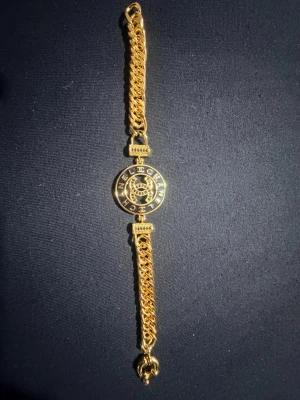 Guldigt armband  - Snyggt guldigt armband. Armbandet har dubbla kedjor och en klassisk karbinhake. Perfekt för dig som vill ha en lyxig accessoar med ikonisk design.