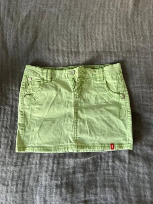 Ljusgrön jeanskjol från Esprit - Trendig ljusgrön jeanskjol från Esprit med klassisk femficksmodell, bälteshällor och knappgylf. Kjolen är kort och har låg midja. Perfekt för sommaren!