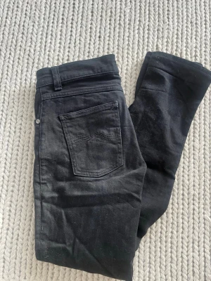 Slim jeans Nudie lean dean - Säljer ett par svarta skinny jeans från Nudie Jeans med klassisk femficksmodell och diskret broderad bakficka. Jeansen har normal midja och är tillverkade i stretchig denim för en bekväm passform modell lean dean