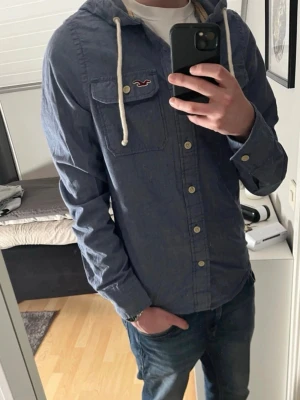 Vintage Hollsiter skjorta med huva - Säljer nu en snygg skjorta från Hollister i blå med huva och snörning. Skick 9/10. Tröjan är i storlek M och modellen på bilden är 183 och väger 67 kilo. Kolla gärna in min profil för liknade plagg. Rabatt vid köp av flera. Skriv om ni har några mer funderingar 😊 