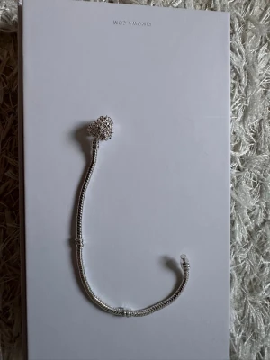 Silverfärgat armband med pärldetalj - Snyggt armband i silverfärg med en dekorativ pärldetalj som ger en exklusiv känsla. Armbandet har en tunn, elegant kedja och en större pärlformad dekoration med gnistrande yta. Perfekt accessoar för att lyfta din stil.