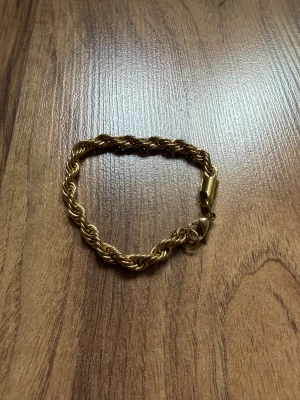 Guldfärgat cordell armband - Snyggt guldfärgat armband med tvinnad kedja och robust lås. Perfekt accessoar för att lyfta din stil med en klassisk touch. Armbandet har en elegant och tidlös design som passar till många olika outfits.