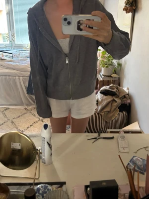 Grå zip hoodie med huva - En enkel och stilren grå hoodie med dragkedja framtill och huva. Hoodien har långa ärmar och ribbade muddar vid ärmslut och nederkant. Perfekt för en avslappnad look och funkar till det mesta. Materialet känns mjukt och bekvämt.