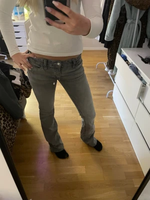 Grå bootcut jeans  - Säljer ett par grå bootcut jeans med vita kontrastsömmar och snygga detaljer på bakfickan från Gina tricot. Dom har en liten svart fläck på framsidan av byxan (bild 4) 