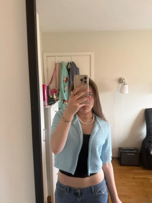 Ljusblå cropped kofta från Zara - Söt ljusblå cropped kofta från Zara med rund halsringning och öppen framtill. Koftan är stickad i ett mjukt material och har en enkel, stilren design som passar perfekt till jeans eller kjol.