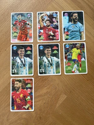 Samling fotbollskort Adrenalyn XL - Säljer en samling med sju fotbollskort från Adrenalyn XL-serien. Korten har färgstarka motiv med spelare i olika landslags- och klubbtröjor, bland annat Argentina, Spanien, Liverpool och Manchester City. Korten är tillverkade i glansig kartong och har holografiska effekter.