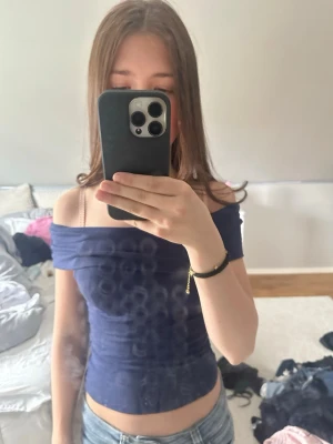 Mörkblå offshoulder topp - Snygg mörkblå offshoulder topp med tight passform och croppad längd. Perfekt för dig som vill ha en enkel men stilren look. Materialet känns mjukt och stretchigt, vilket gör den bekväm att bära. Passar till jeans eller kjol för en cool outfit.