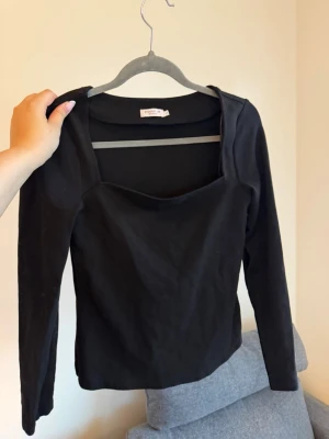 Svart långärmad tröja - Stilren svart långärmad tröja i ett något tjockare material. En fyrkantig urringning som gör tröjan lite mer elegant. 