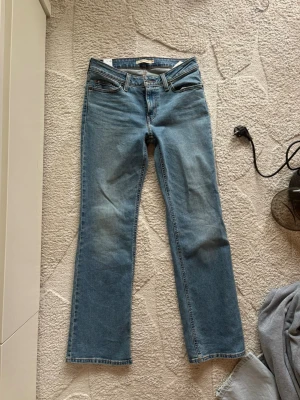 Blå Superlow Bootcut Jeans - Säljer ett par blå bootcut jeans! Klassisk femficksmodell med snygg tvätt och raka ben. Perfekta för dig som gillar en avslappnad och trendig look. Jeansen har kontrastsömmar och är tillverkade i denim.