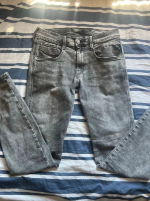 Replay grå slim fit jeans Hyperflex - Snygga grå slim fit jeans från Replay, modell Anbass Hyperflex. Jeansen har fem fickor, normal midja och stretchigt material som ger extra komfort. Perfekta för en trendig och ”grisch” stil.