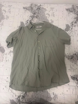 Ljusgrön kortärmad linneskjorta - Snygg ljusgrön skjorta från Dressman i linne. Skjortan har korta ärmar, klassisk krage, bröstficka och knäppning framtill. Perfekt för en avslappnad och stilren look.
