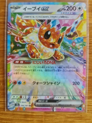 Eevee ex Pokémonkort holo - Säljer ett Eevee ex Pokémonkort med holografisk regnbågseffekt. Kortet har färgglad design med Eevee i mitten och japansk text. Det är från Scarlet & Violet-serien, nummer 126/187. Perfekt för samlare eller Pokémonfans.