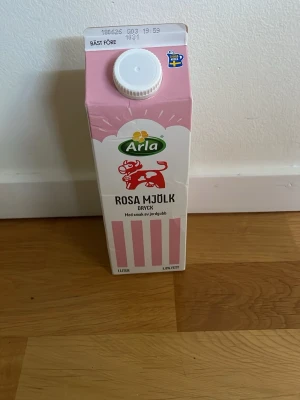 Arla rosa mjölkdryck jordgubb 1L TOM! - En liter rosa mjölkdryck från Arla med smak av jordgubb. Förpackningen är rosa och vit med ränder och har en skruvkork på toppen. Perfekt för dig som gillar smaksatt mjölk och vill ha något annorlunda att dricka.