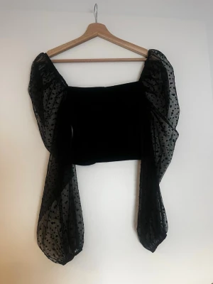 Svart topp med puffärmar från ASOS - Trendig svart topp från ASOS DESIGN med transparenta puffärmar i mesh och prickigt mönster. Liten i storleken!!