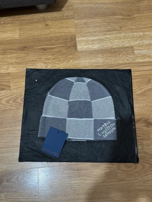 Grå-rutig mössa från zara med en lapp - Säljer en snygg grå mössa från zara med rutigt mönster i olika nyanser av grått. Mössan har vikt kant och textdetalj på sidan. Perfekt accessoar för dig som gillar exklusiv streetwear och vill sticka ut med stil, med en lapp.