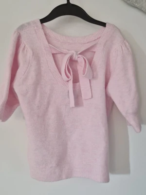 Ljusrosa stickad tröja med rosett - Säljer en fin stickad tröja från Pieces i storlek S. Färgen är en ljusrosa nyans och den har en snygg detalj med rosett i ryggen. Tröjan är sparsamt använd och i bra skick. Perfekt för vardagsbruk eller när du vill ha något lite extra.