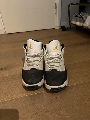 Jordan sneakers svart/vit/gul/grön - Snygga Jordan sneakers med svart och vit ovandel, gula detaljer på tungan och loggan samt grön häl. Skorna har en sportig design med mesh och syntetmaterial, vita snören och låg profil. Perfekta för dig som gillar streetstyle och basketinspirerat mode.