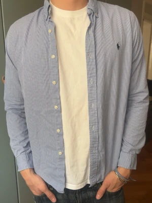 Blårandig skjorta från Ralph Lauren - Skjorta från Ralph Lauren, inga defekter. Modellen är 187 cm, väger 80 kg och brukar klä i M.   Storlek på skjorta M slim fit  Mått -|-  Axelmått: 44 cm  Längd: 72 cm  Byst: 52 cm  Armar: 63 cm   Leverans sker dagen efter senast. Skriv om du har nån fråga✨