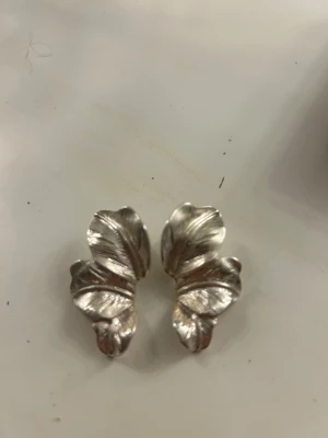 Silvriga örhängen i bladform - Säljer dessa bladformiga örhängena från Ullared. Använda fåtal gånger. Säljer då jag inte känner mig som en silver tjej längre.