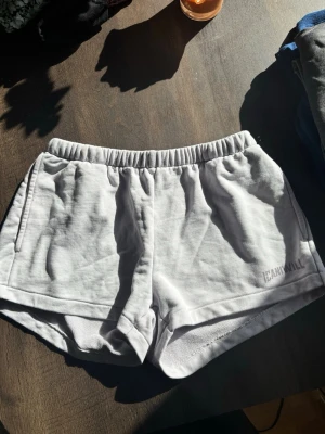 Lila shorts från ICANIWILL - Säljer ett par lila shorts från ICANIWILL med elastisk midja och diskret logga på benet. De är tillverkade i mjukt bomullsmaterial och har en klassisk, loose passform som är perfekt för träning eller chill dagar.