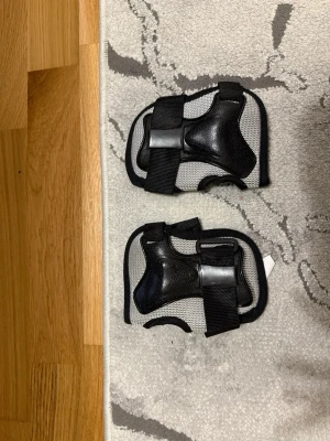 Stiga handledsskydd svart/grå - Säljer ett par handledsskydd från Stiga i svart och grått med robust plastskydd och justerbara kardborreband. Perfekt för skate, inlines eller andra sporter där du vill skydda handlederna. Materialet är en kombination av mesh och hårdplast.