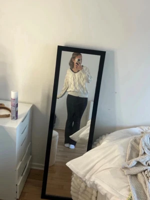 Vit stickad tröja med spets från SHELAY - Vit stickad tröja från SHELAY med v-ringning och svart spetskant. Tröjan har ett snyggt mönster med hålstickning och ribbade muddar vid nederkant och ärmslut. Perfekt för dig som gillar en stilren look med en twist.