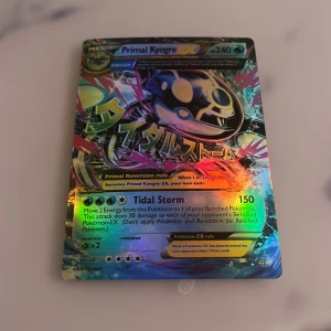 Primal Kyogre EX Pokémonkort - (Psa 9) Säljer ett holografiskt Primal Kyogre EX Pokémonkort med 240 HP och attacken Tidal Storm. Kortet har en färgglad design med japansk text och är en del av Pokémon EX-serien. Perfekt för samlare eller spelare som vill förstärka sin kortlek. Jag vet inte om den är 100% äkta men den borde vara det