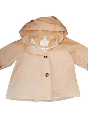 Beige anorak parkasjacka med huva Zara stl 86 - Stilren beige regnjacka från Zara med huva och två framfickor. Jackan har knäppning med stora knappar och en klassisk rak passform. Perfekt för regniga dagar och enkel att matcha med olika outfits.    Storlek 86 unisex.                                                     Mycket fint skick, dock en vag fläck på vänster ficka men inget som stör. Djur och rökfritt hem 