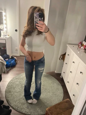 Vit croppad ribbad topp från Zara - Säljer en vit croppad topp från Zara med ribbad struktur. Toppen har korta ärmar och rund halsringning, perfekt för en trendig och enkel look. Passar till både jeans och kjol för en snygg outfit.