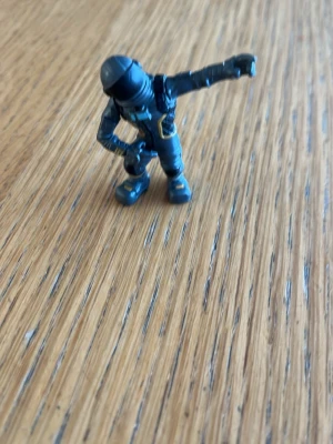 Blå actionfigur i plast - Liten actionfigur i blått med svarta detaljer och hjälm. Figuren har en futuristisk dräkt och står i en pose med ena armen utsträckt. Tillverkad i plast och passar perfekt som samlarobjekt eller dekoration.