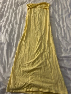 Gul långklänning från ASOS DESIGN - Säljer en ljusgul långklänning från ASOS DESIGN. Klänningen är axelbandslös och har en tajt passform som formar kroppen. 
