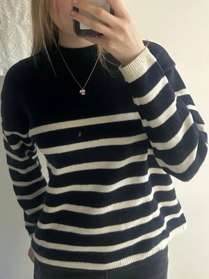 Randig stickad tröja i marinblått och vitt - Säljer en stickad tröja med breda marinblå och vita ränder. Tröjan har rund halsringning, långa ärmar och ribbade muddar vid ärmslut och nederkant. Varm, söt och trendig!