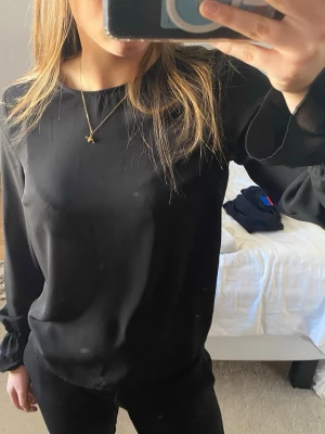 Svart blus - Stilren svart blus i tunt, lätt och något transparent material från Gina Tricot. Blusen har rund halsringning och långa ärmar med diskreta resårdetaljer vid ärmarna. Säljs pga att den inte kommer till användning 💕Bara att höra av dig vid frågor eller bilder💕
