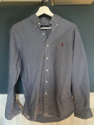 Ralph lauren skjorta - Ralph lauren skjorta i storlek M i vit blått rutigt tema med vin röd logga. Riktigt fint skicka utan några deffekter över huvudtaget.