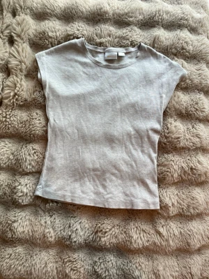 Ljusgrå basic t-shirt från Gina Tricot - En enkel och stilren ljusgrå t-shirt från Gina Tricot. Modellen är kortärmad med rund halsringning och har en normal passform. Tillverkad i mjuk bomull som känns skön mot huden. Perfekt att matcha med jeans eller kjol.